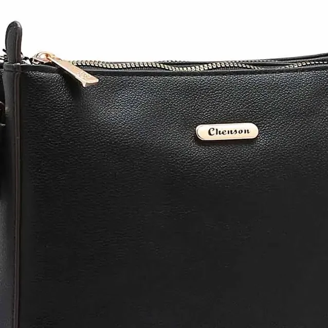 Close na placa metálica dourada com logo Chenson em bolsa preta transversal